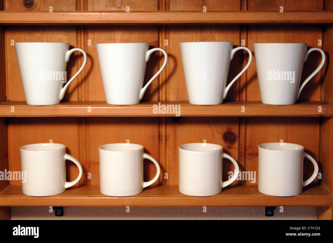 White mugs displayed on wooden shelves Stock Photo