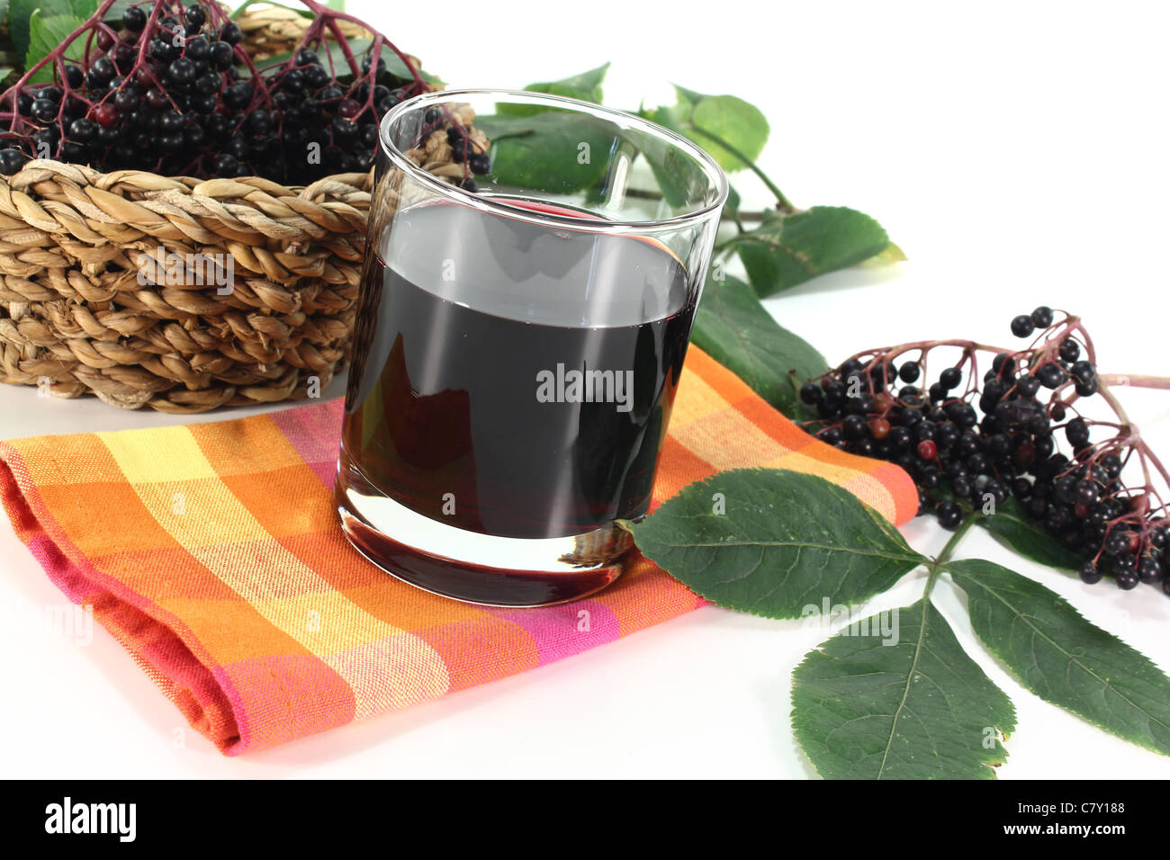 Elderberry juice with elder berries and leaves on a white background