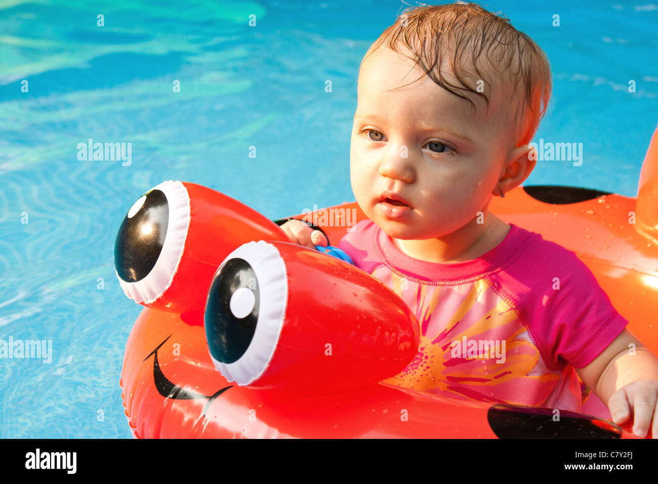 Baby girl staring while floating in a pool Stock Photo