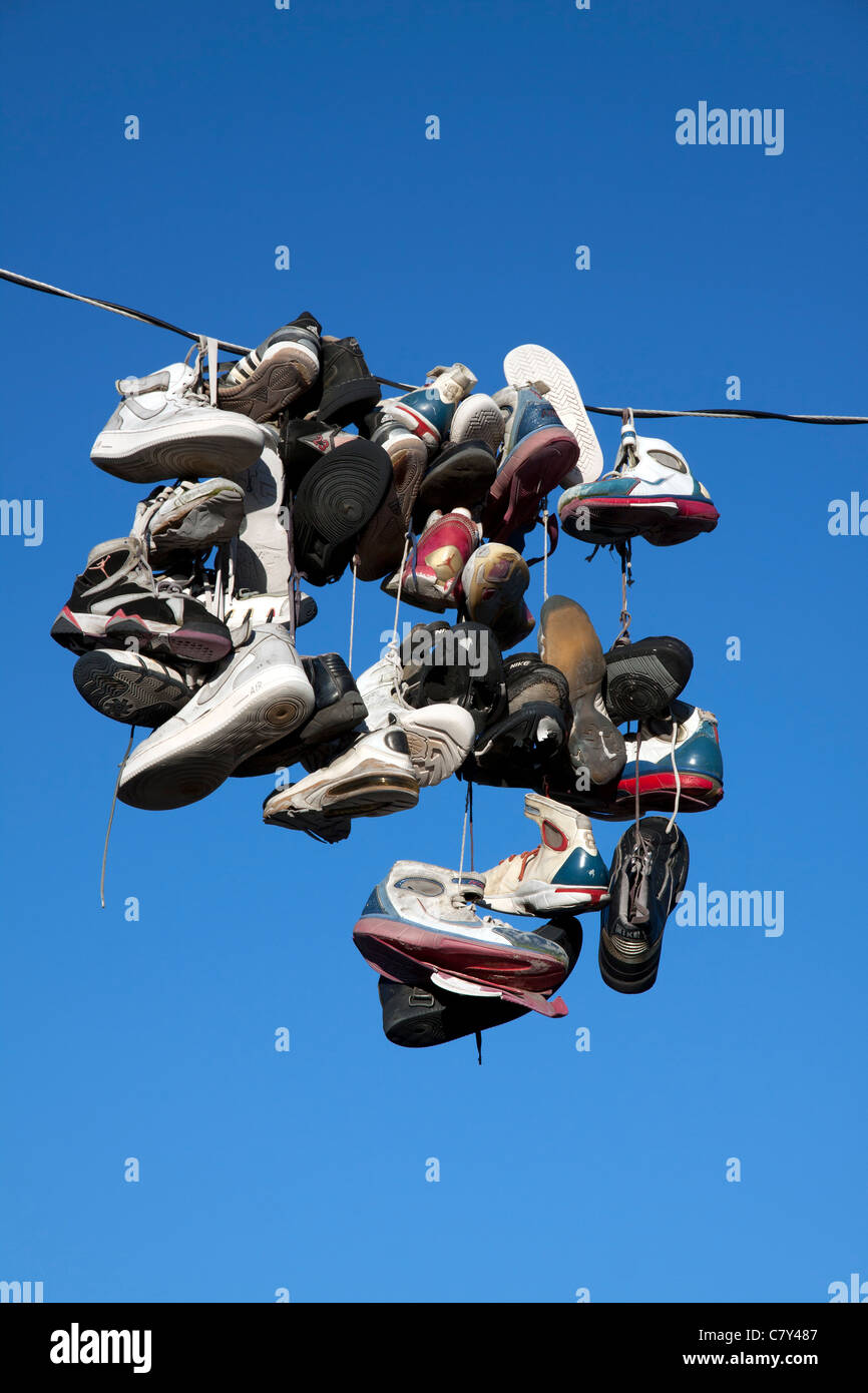 Various types of tennis shoes hanging from a power line in Detroit Michigan USA Stock Photo