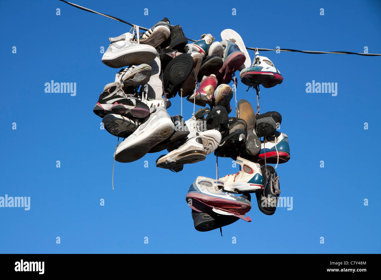 Various types of tennis shoes hanging from a power line in Detroit Michigan USA Stock Photo