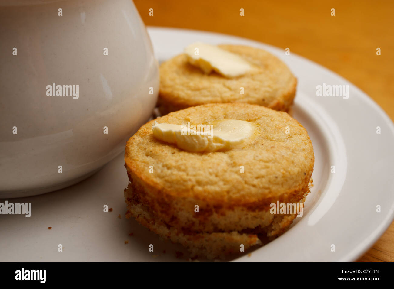 Cupcake style buttered cornbread on a white plate with bowl of soup Stock Photo