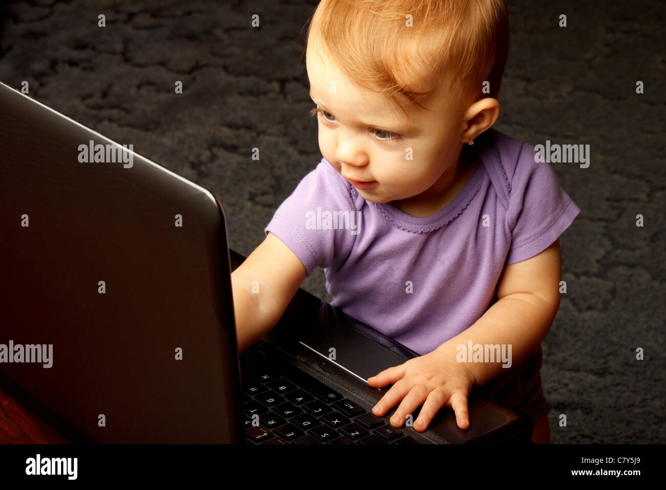 Cute baby pointing at lit laptop screen Stock Photo