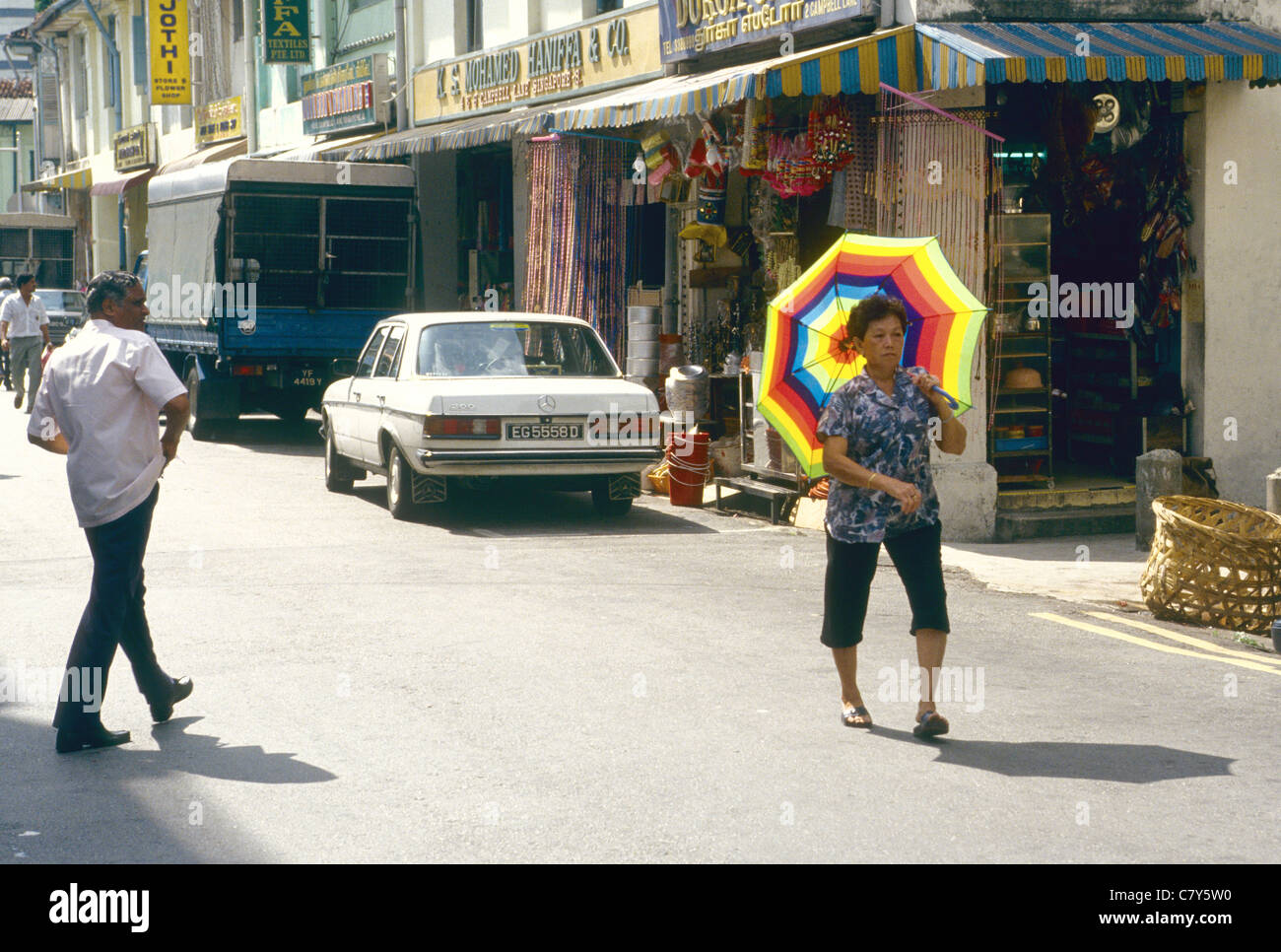 A womal carrying a colourful umbrella walking in Singapore's China Town