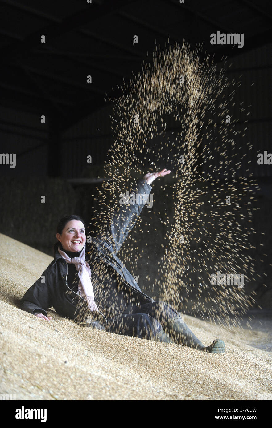 A WOMAN IN A GRAIN STORE THROWING GRAIN INTO THE AIR RE FARMING COSTS CROPS CEREALS FOOD PRICES HEALTH BENEFITS HEALTHY ETC UK Stock Photo