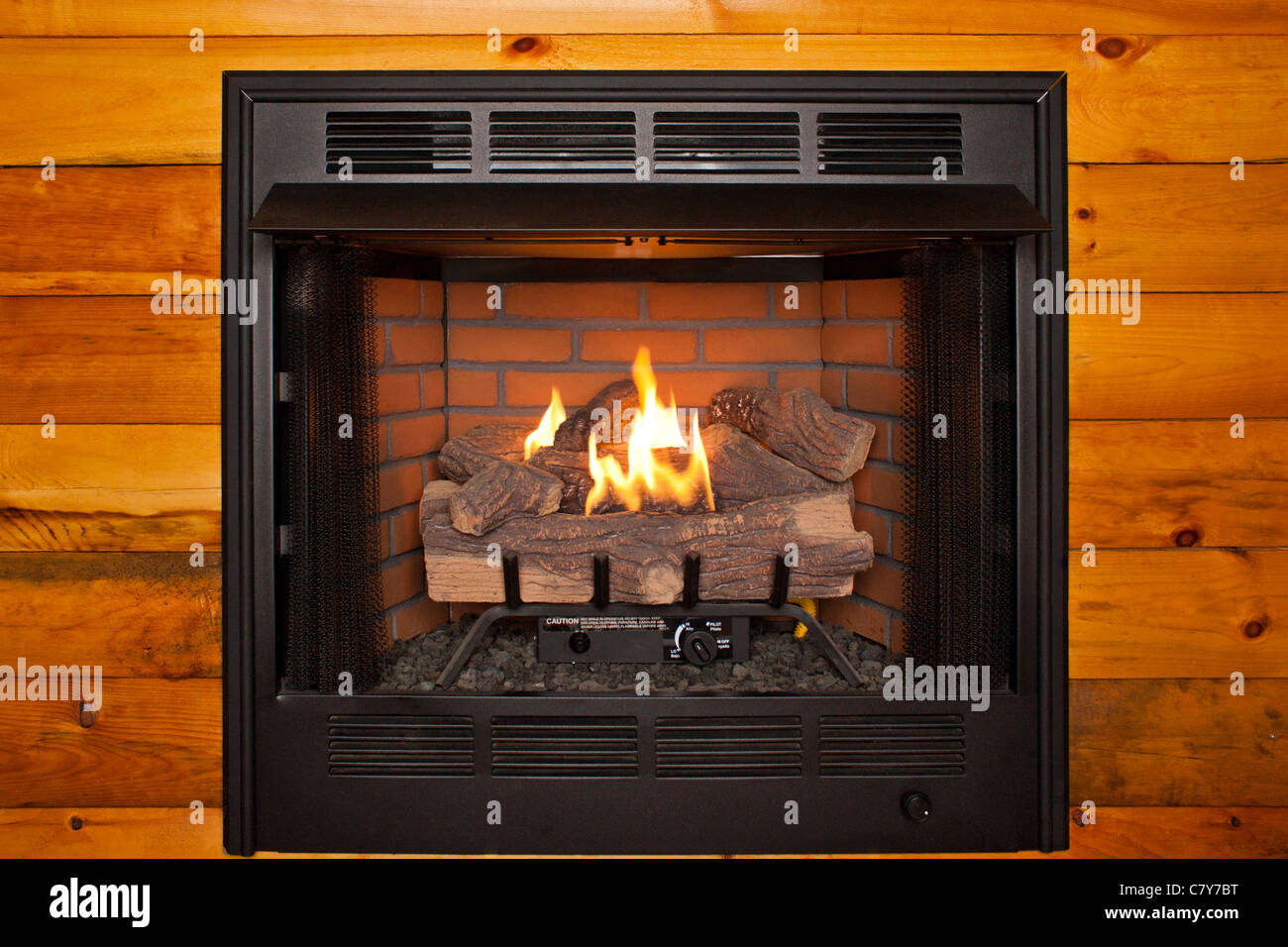 Lit electric fireplace built into log cabin wall Stock Photo