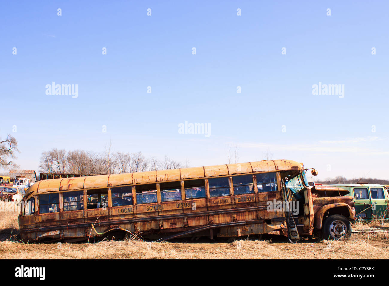 Old rusty school bus partly collapsed in salvage yard Stock Photo