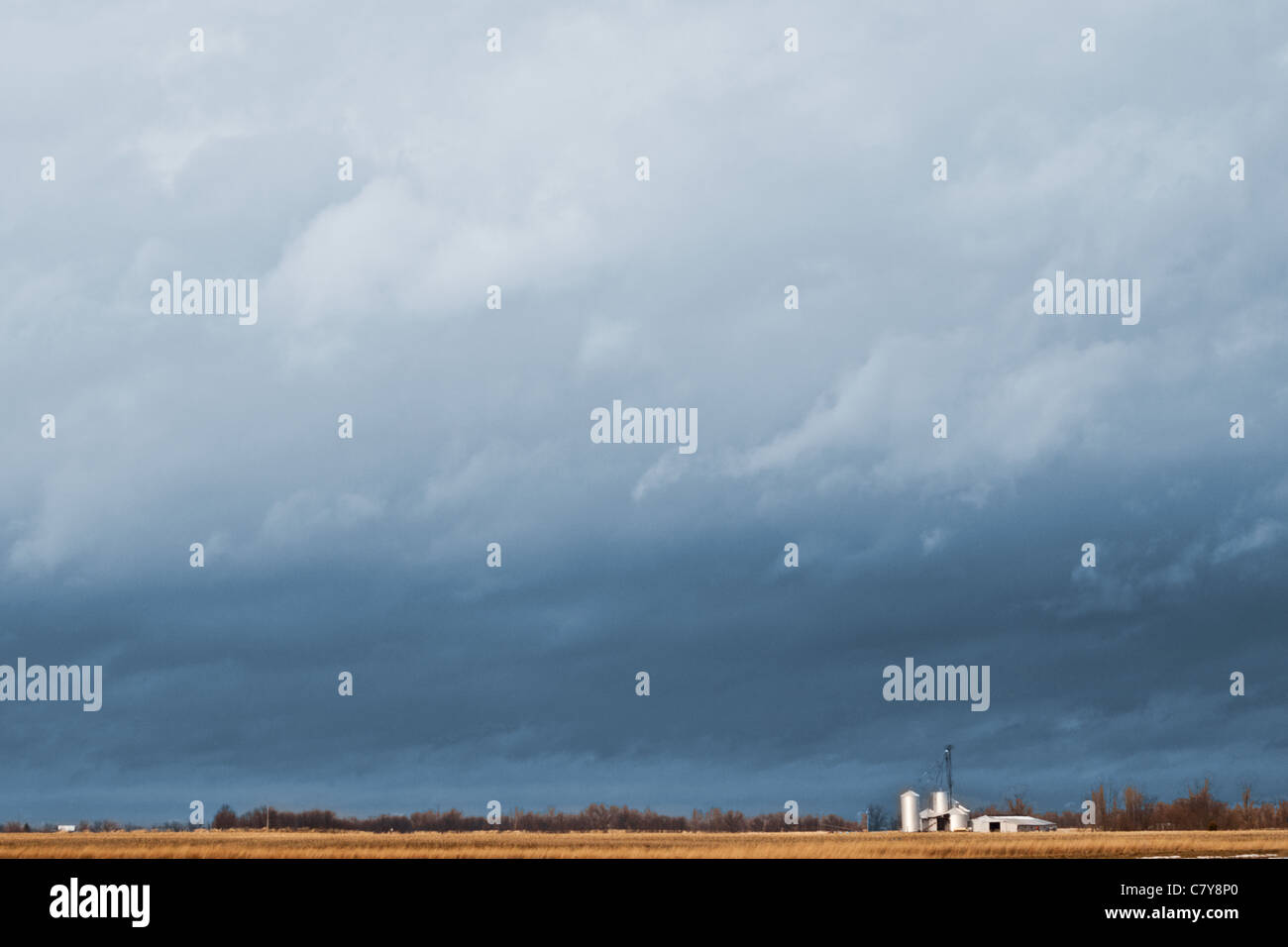 Bluish storm sky hovering over a small farm and field Stock Photo