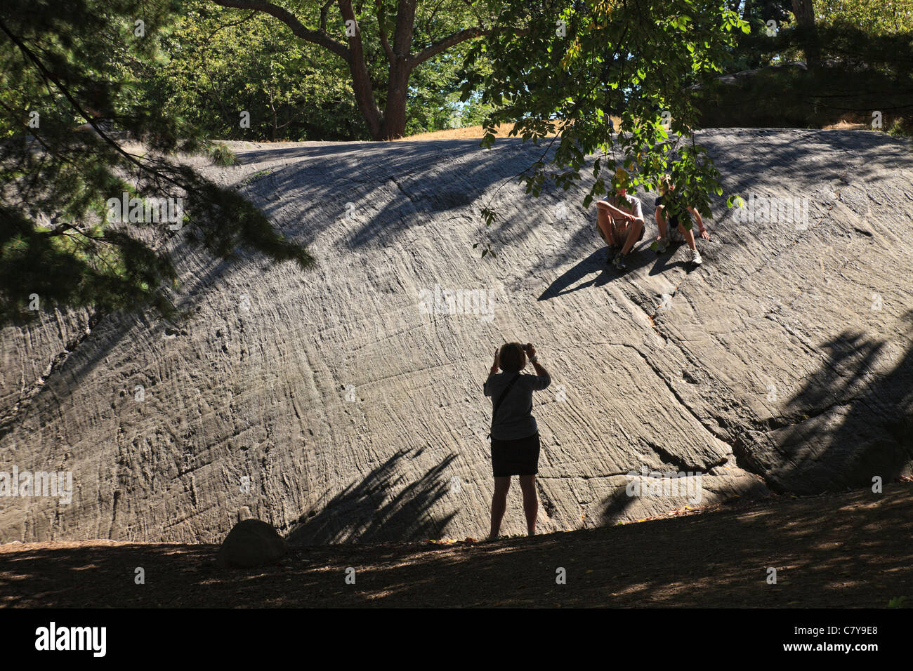 Mother takes a photo of children on a granite outcropping in Central Park (NR). Stock Photo