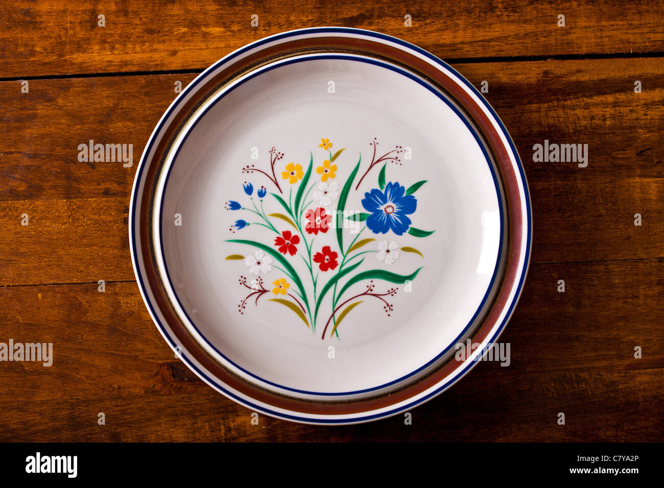 Top view of a stack of floral plates on a wooden surface Stock Photo