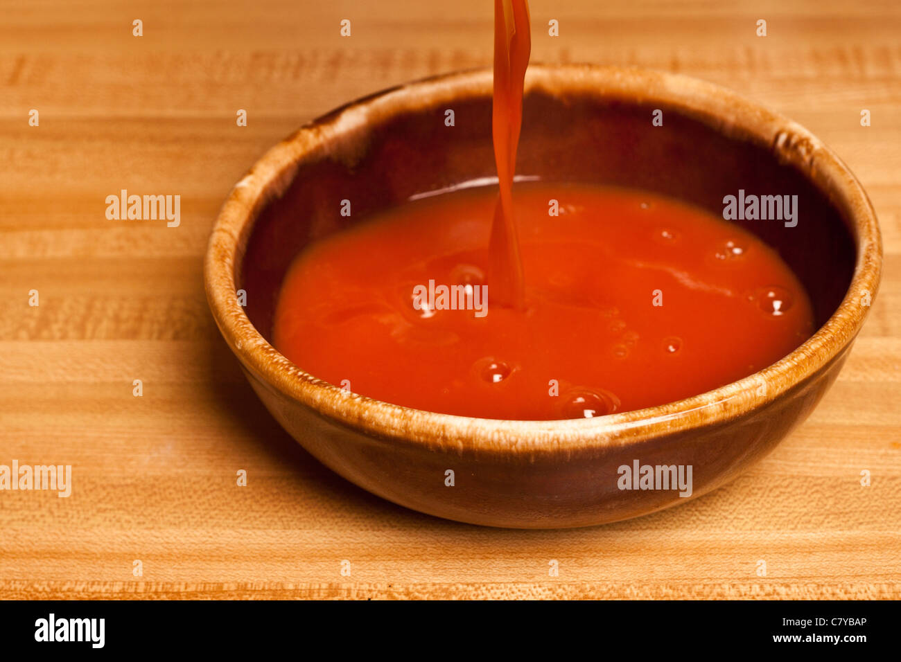 Tomato soup being poured into a ceramic bowl Stock Photo