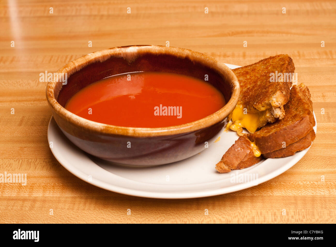 Tomato soup sharing a plate with a cut grilled cheese sandwich Stock Photo