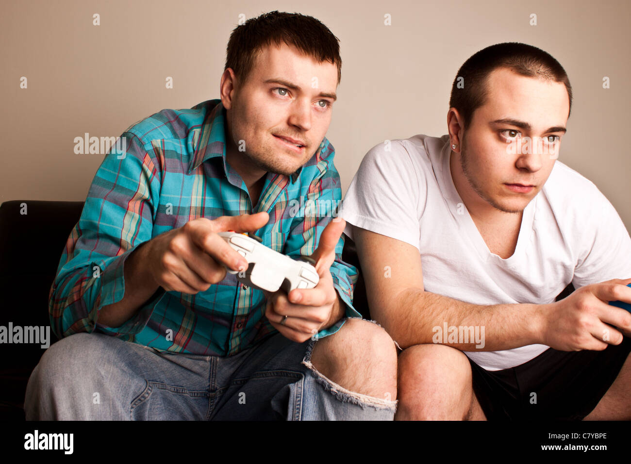 Two attractive guys concentrating while playing video games Stock Photo