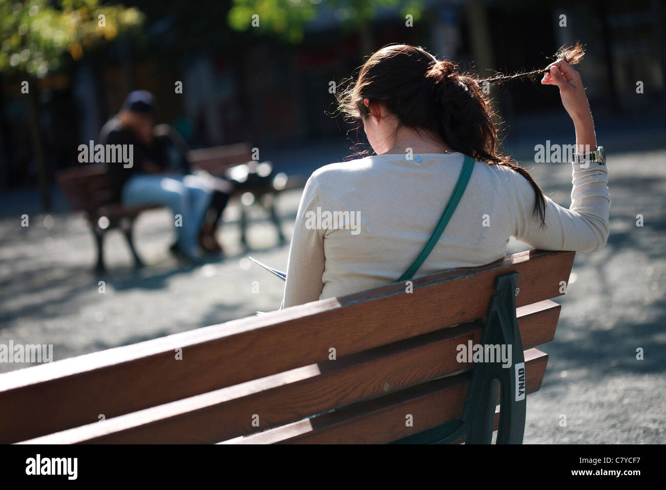 Girl play with her hair on a bench in the centre of Frankfurt am Main