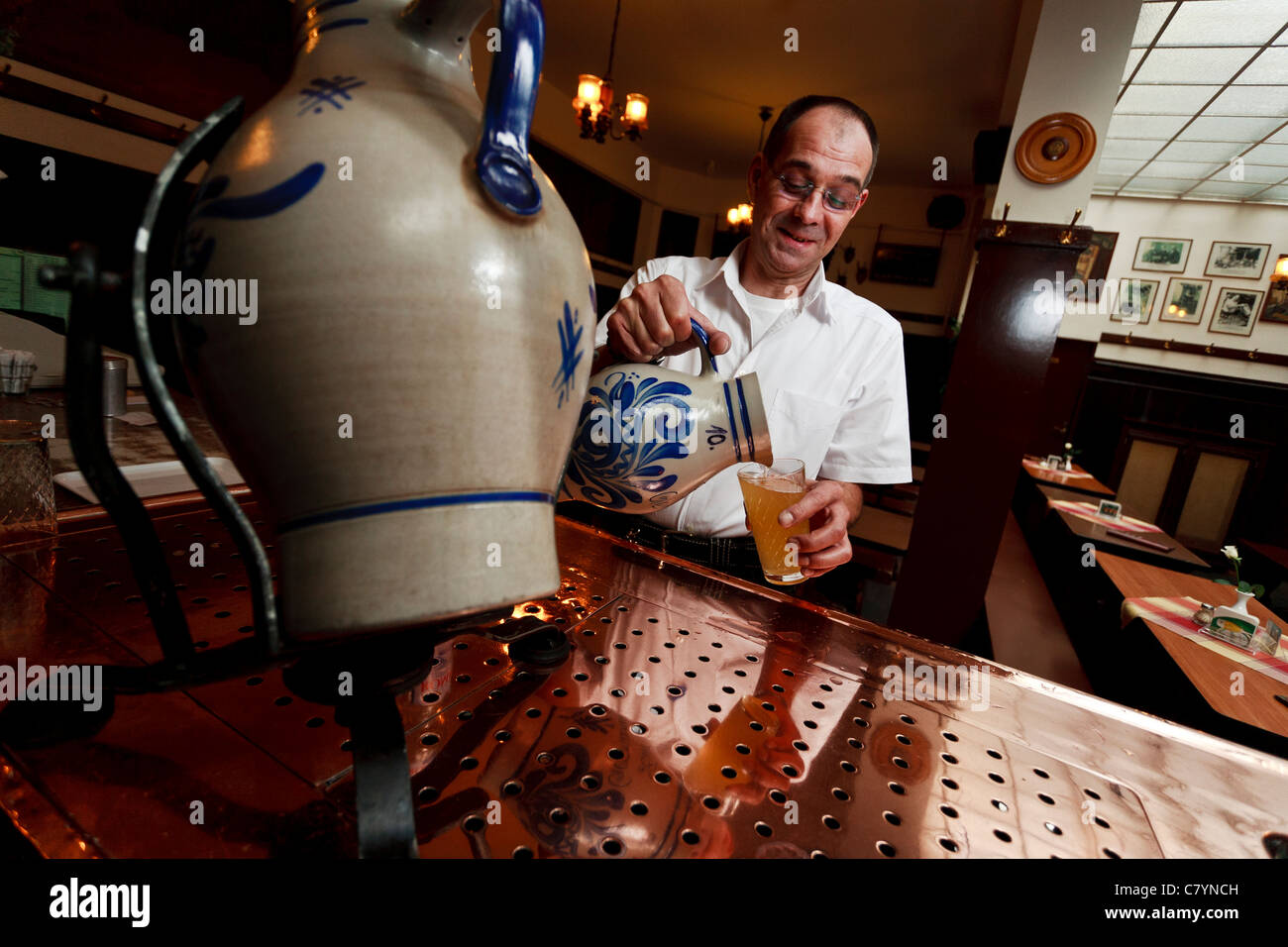 German barman serving the famous Sachsenhausen Apfelwein out of a traditional jug. Stock Photo
