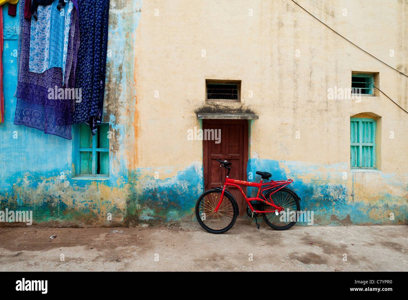 Red Indian bike leaning against a house in Indian street. Puttaparthi, Andhra Pradesh, India Stock Photo