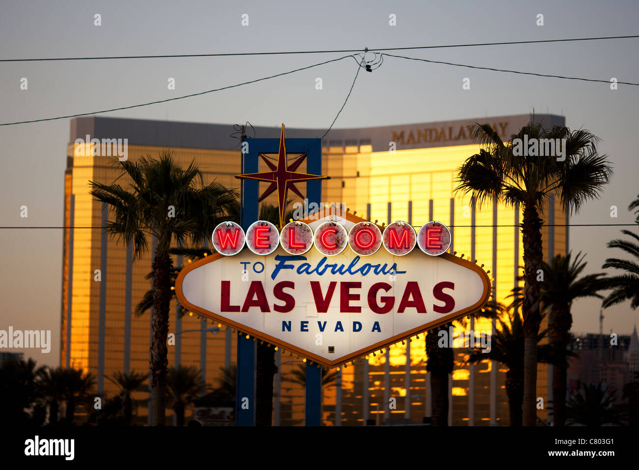 Welcome to Fabulous Las Vegas Sign. The glowing, out of focus Mandalay Bay Resort at sunset highlights the famous sign. Clark County, Nevada, USA. Stock Photo