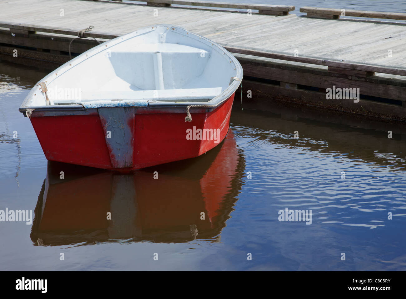 Small  red rowboat next to a dock Stock Photo