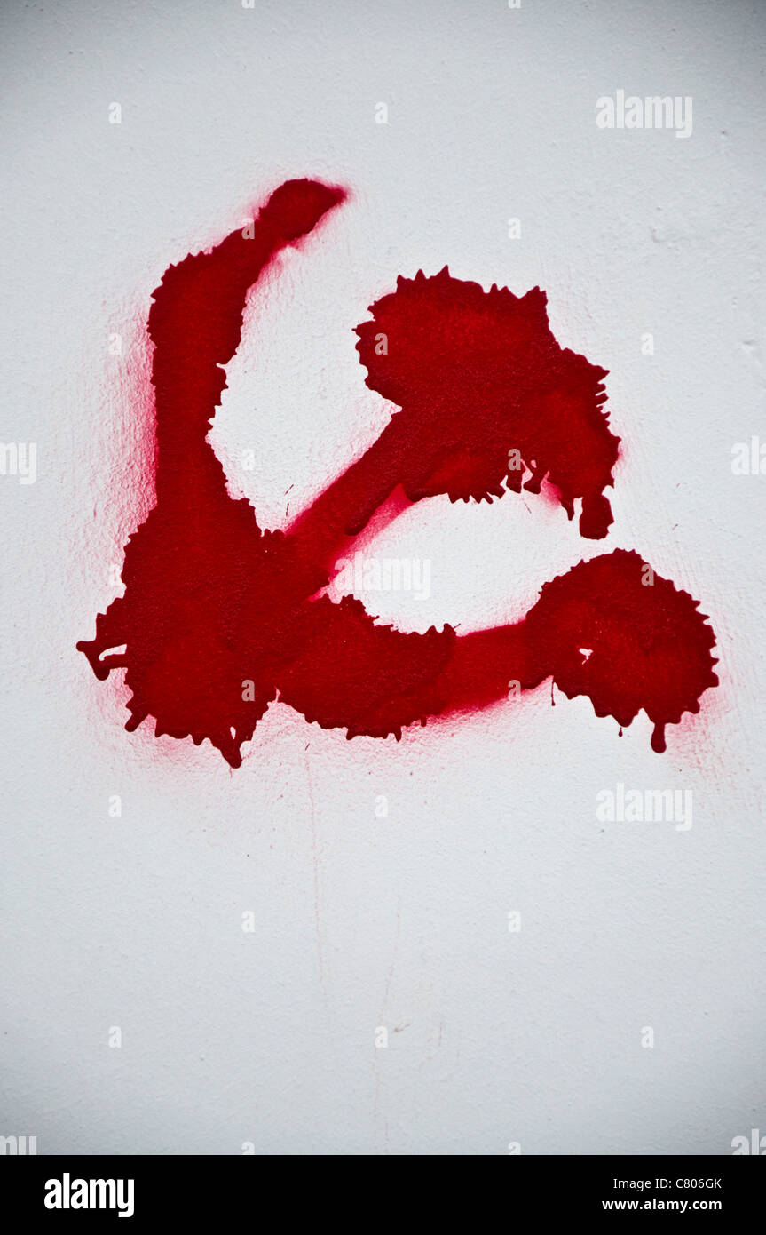Communist symbol of hammer and sickle spray painted on a white wall. Stock Photo