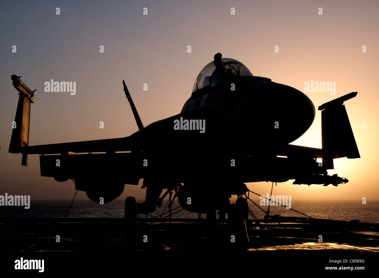 Silhouette of a US Navy F/A-18E Super Hornet parked on the flight deck of aircraft carrier USS Nimitz off the coast of Pakistan. Stock Photo