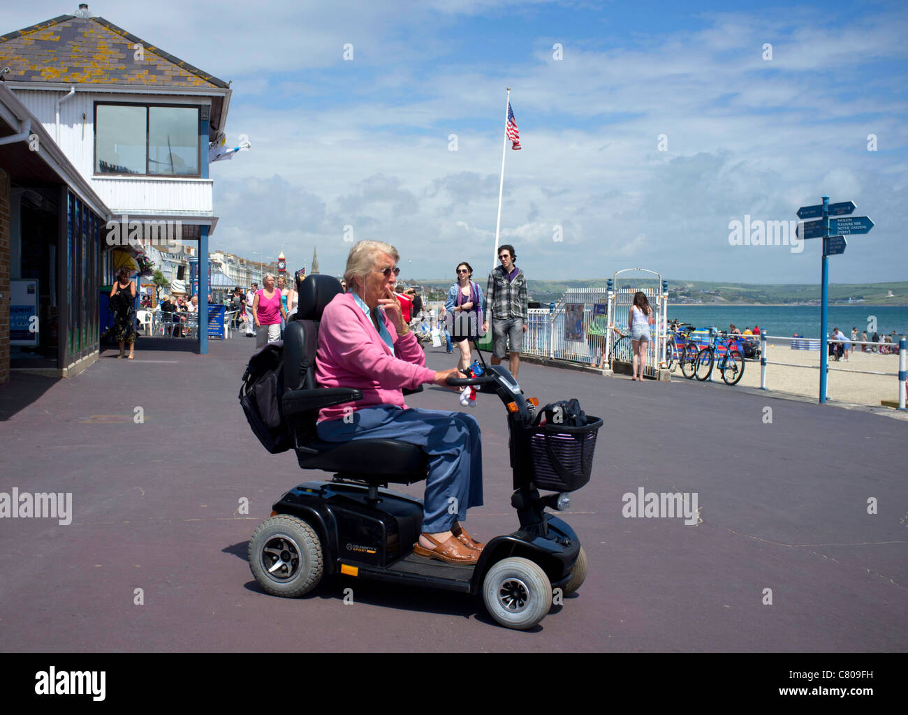 Lady smoking a cigarette on a mobility card on the Promenade by Weymouth beach, Dorset. Stock Photo