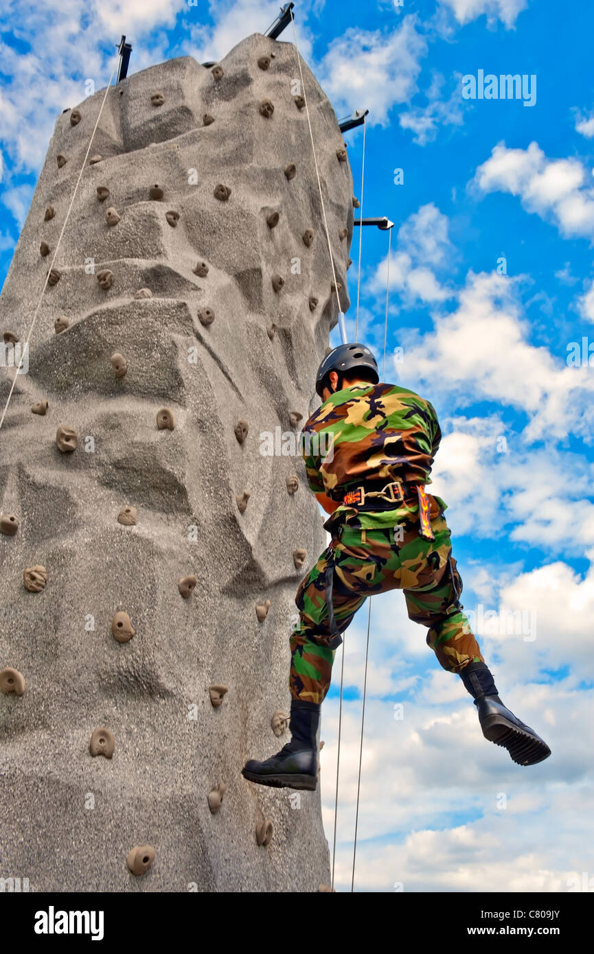 From below, man wearing military camouflage rappelling down portable rock climbing wall for U.S. Army recruiting at NY fair 2011 Stock Photo