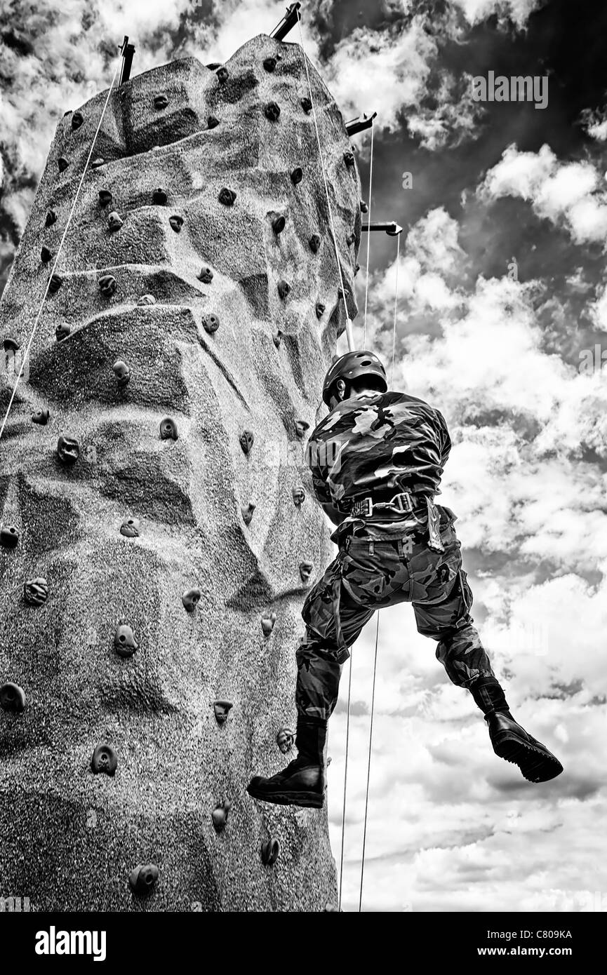 From below, man in military camouflage rappelling down rock climbing wall at U.S. Army recruiting area, Bellmore, NY, 2011 B&W Stock Photo