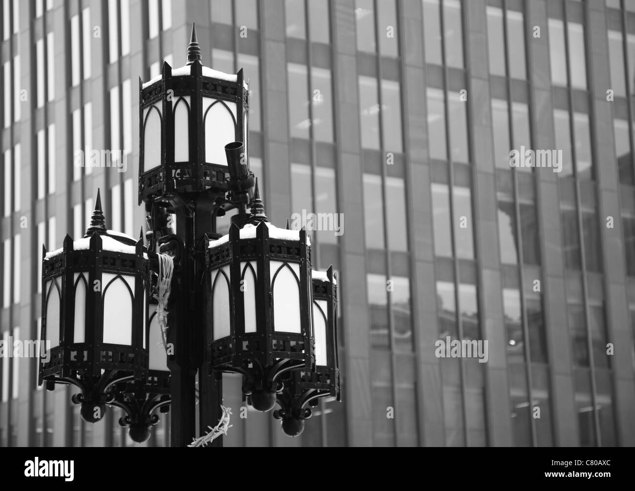 black and white photograph of a iron lamp post in historic downtown Montreal, Quebec, Canada, sky scrapper in the background. Stock Photo