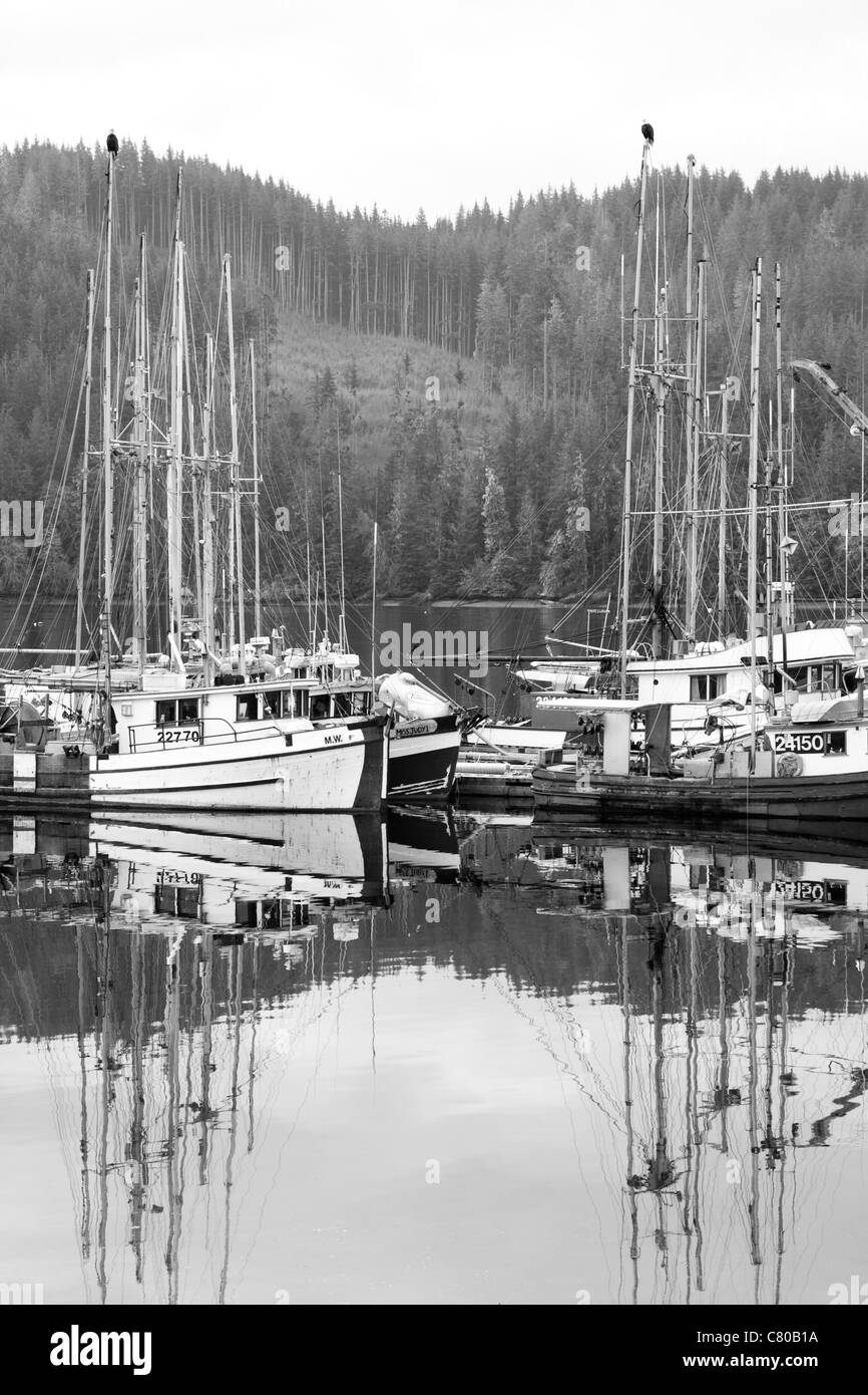 A black and white photograph of the fishing boats in Coal Harbour, British Columbia, Canada. 2 bald eagles sit on top the boats Stock Photo