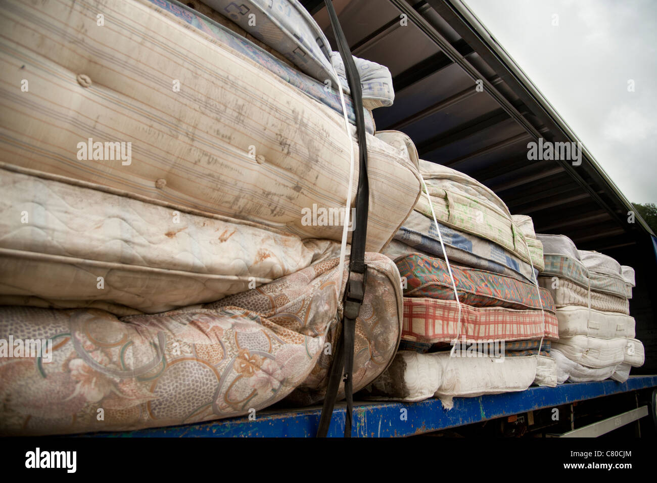 Old mattresses stacked on  ruck awaiting disposal or recycling, UK Stock Photo