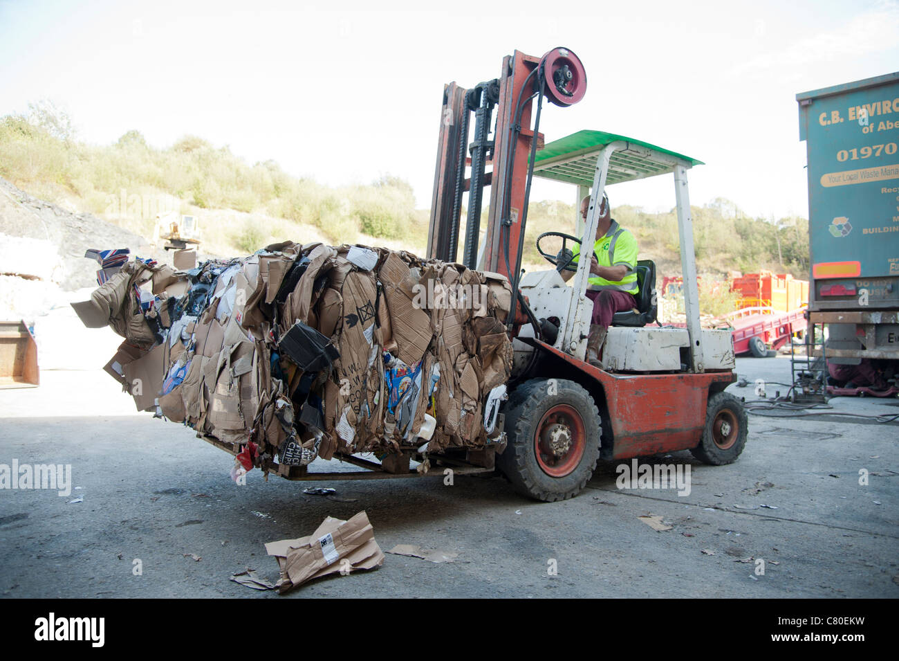 a forklift truck driver stacking Compacted waste cardboard into bales