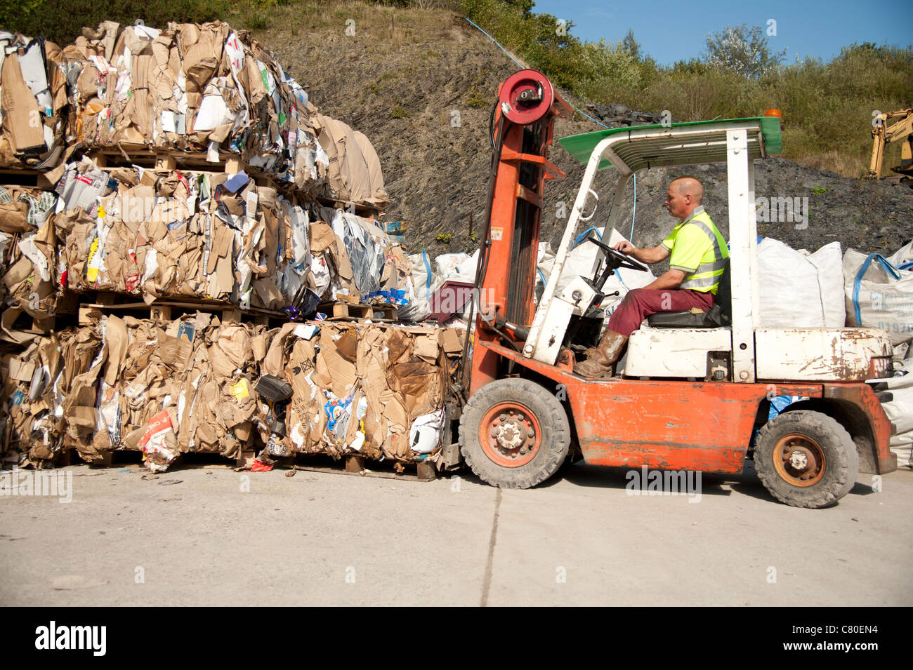 a forklift truck driver stacking Compacted waste cardboard into bales