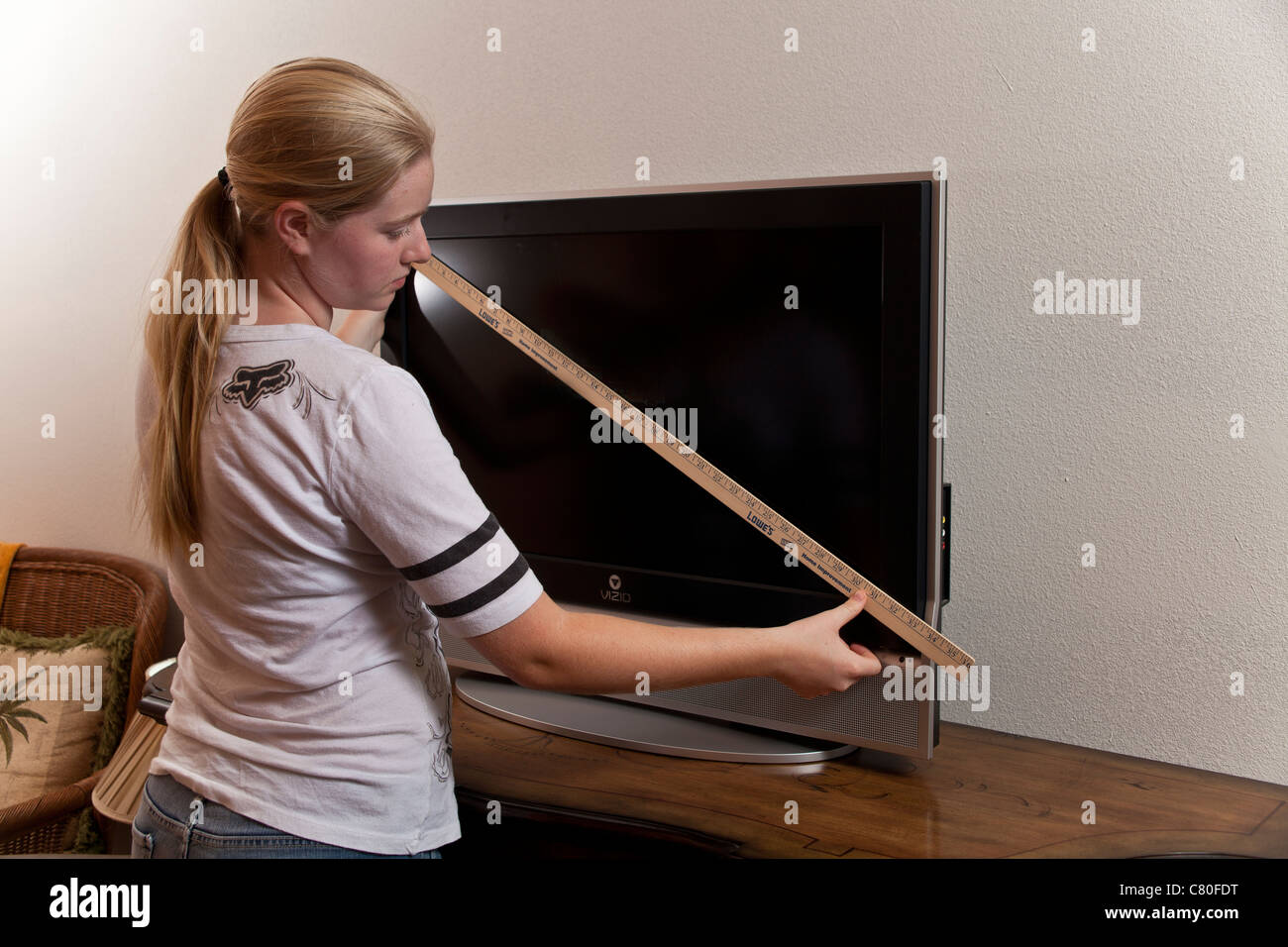 Teenage girl measures the dimensions of a 32 inch TV Screen. MR © Myrleen Pearson Stock Photo