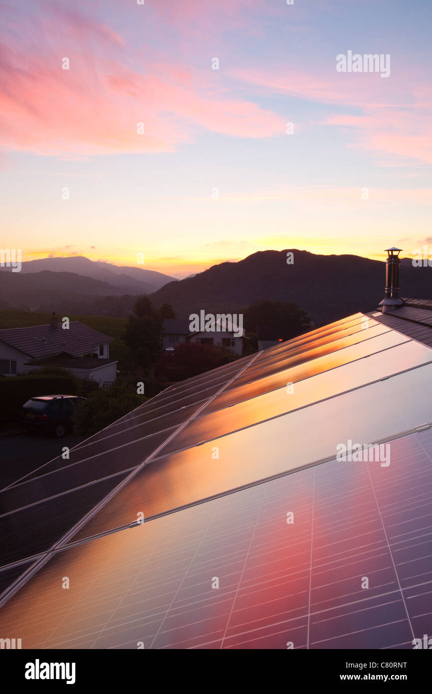 Sunset over a house in Ambleside, Lake District UK, with a 3.8 Kw solar electric panel system on the roof. Stock Photo