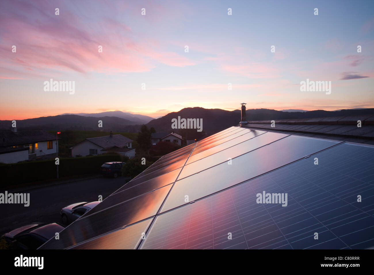 Sunset over a house in Ambleside, Lake District UK, with a 3.8 Kw solar electric panel system on the roof. Stock Photo