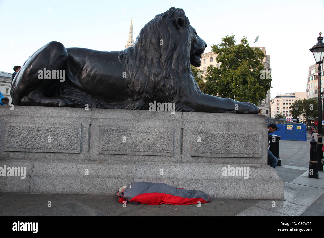 Homeless sleeper underneath one of the lions at Trafalgar Square, London Stock Photo