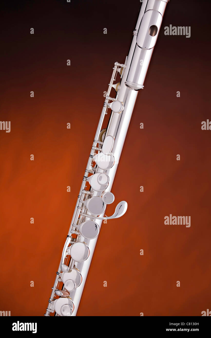 A silver alto flute music instrument on a spotlight gold background with copy space. Stock Photo