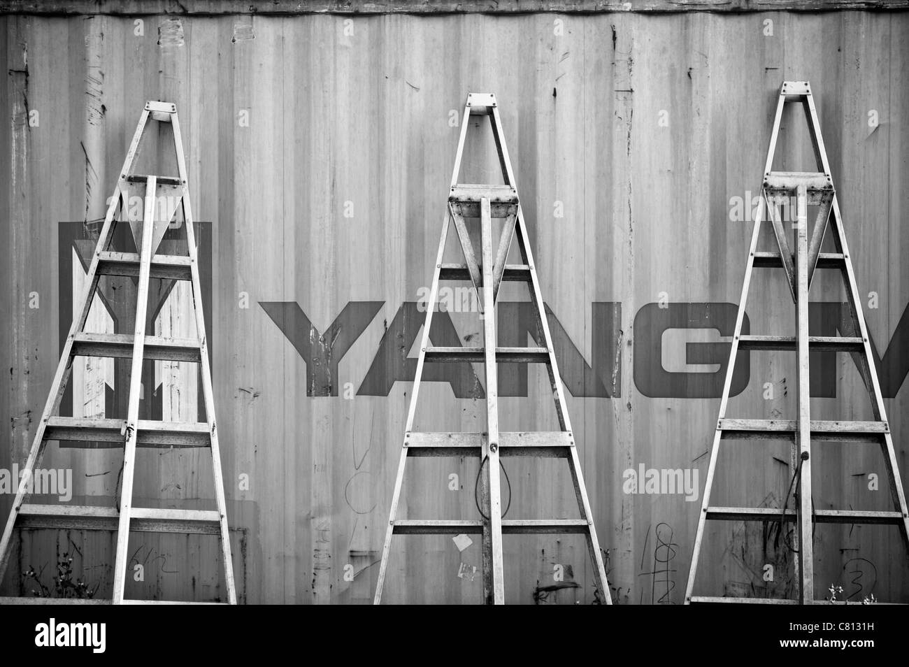 Three fruit picking ladders leaning against a container in an English orchard Stock Photo