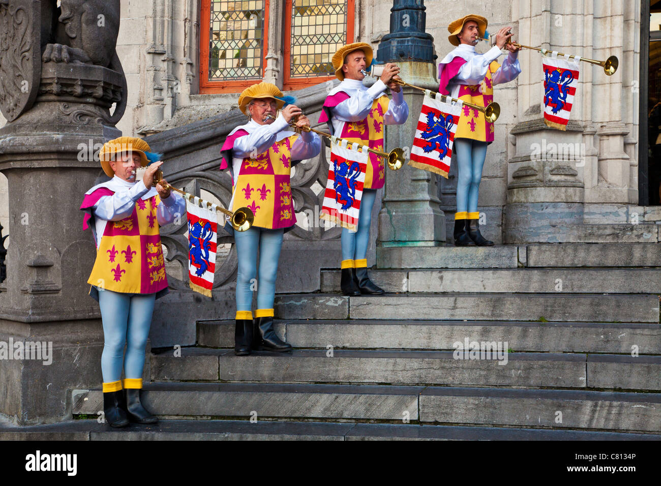 Trumpeters in ceremonial dress playing brass Aida fanfare trumpets before the Provincial Court, Grote Markt, Bruges, Belgium Stock Photo