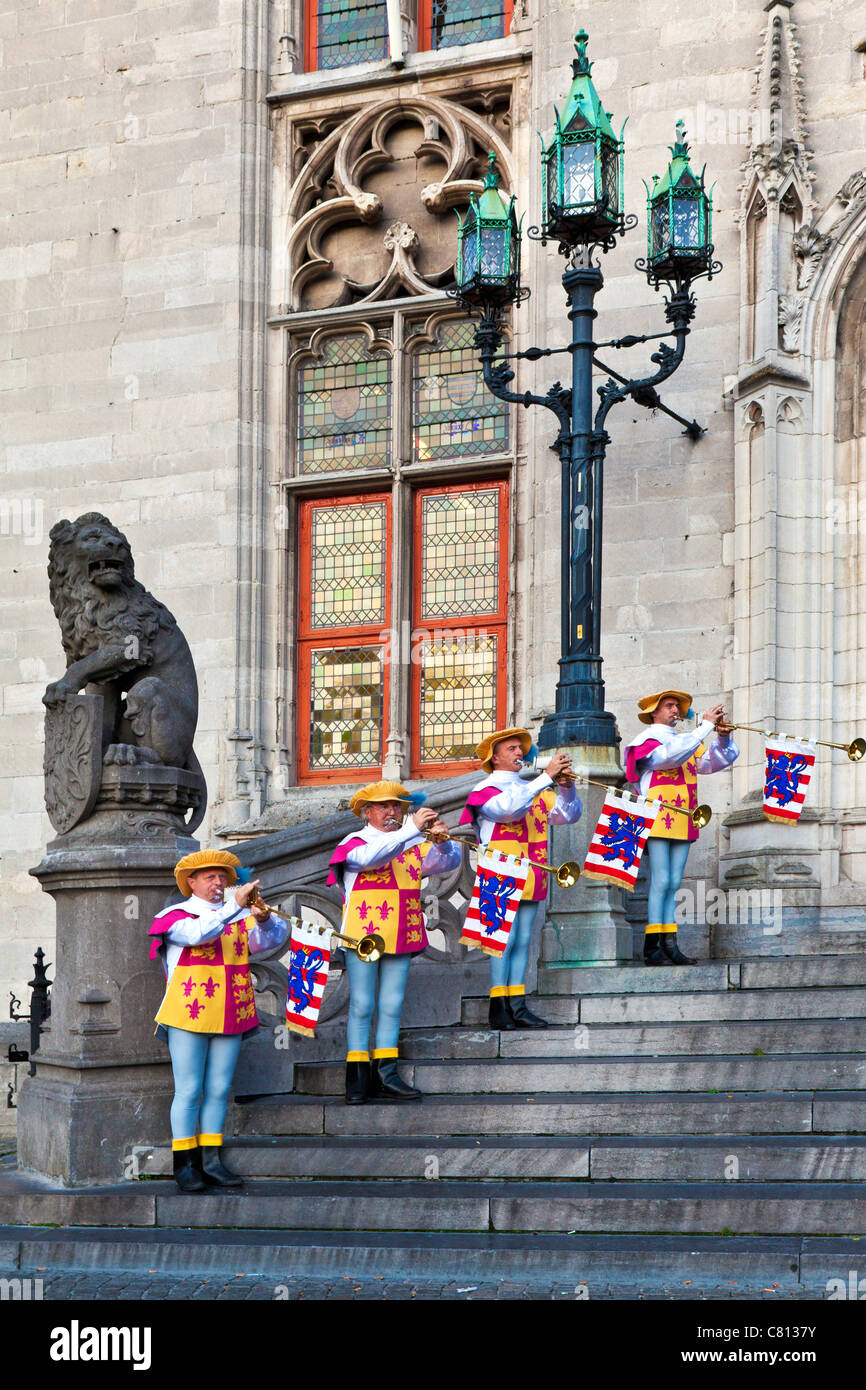 Trumpeters in ceremonial dress playing brass Aida fanfare trumpets before the Provincial Court, Grote Markt, Bruges, Belgium Stock Photo