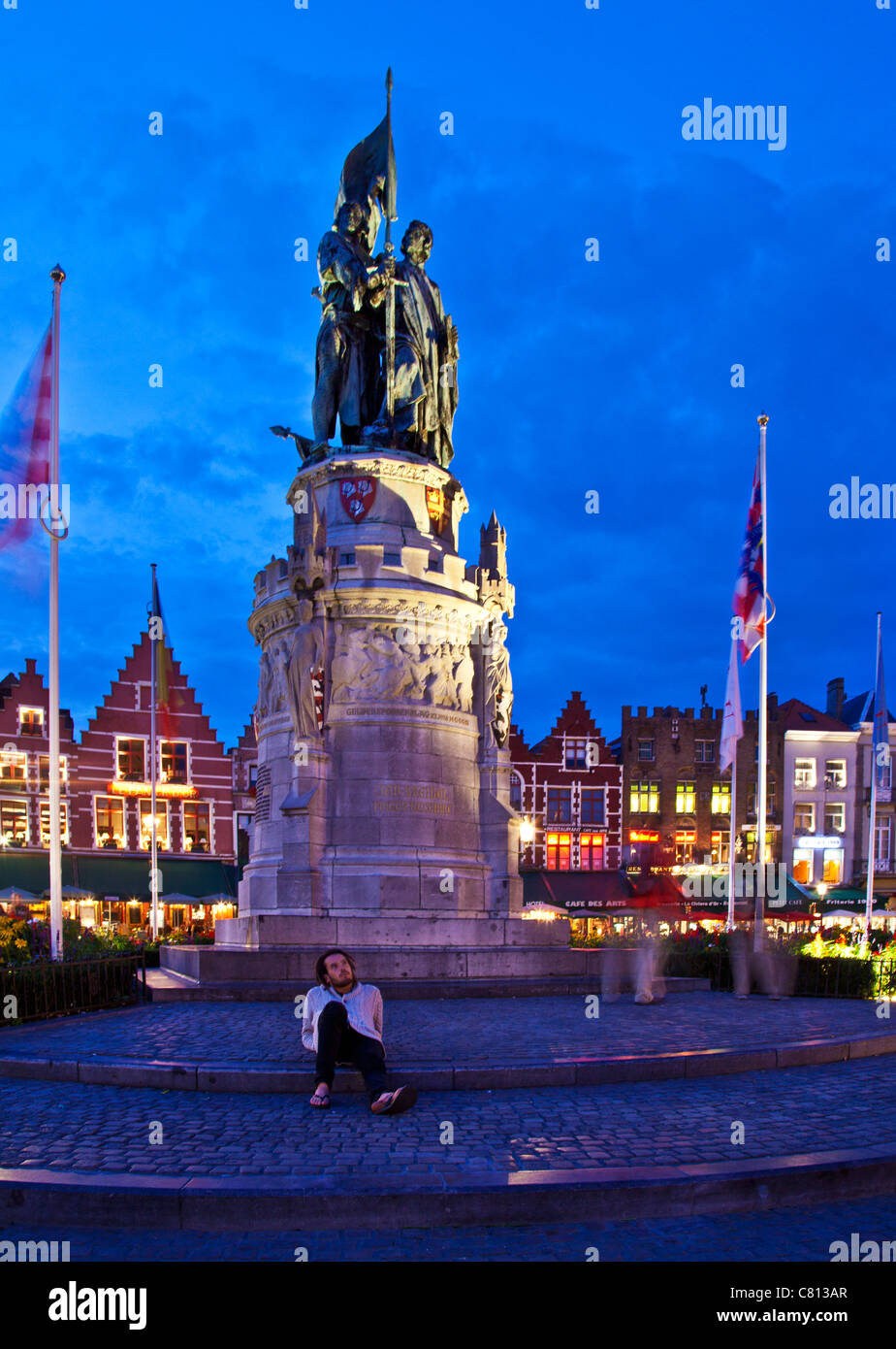 Tourist enjoying the night in front of the statue in the Grote Markt, Market Square, Bruges, Belgium at dusk, twilight. Stock Photo