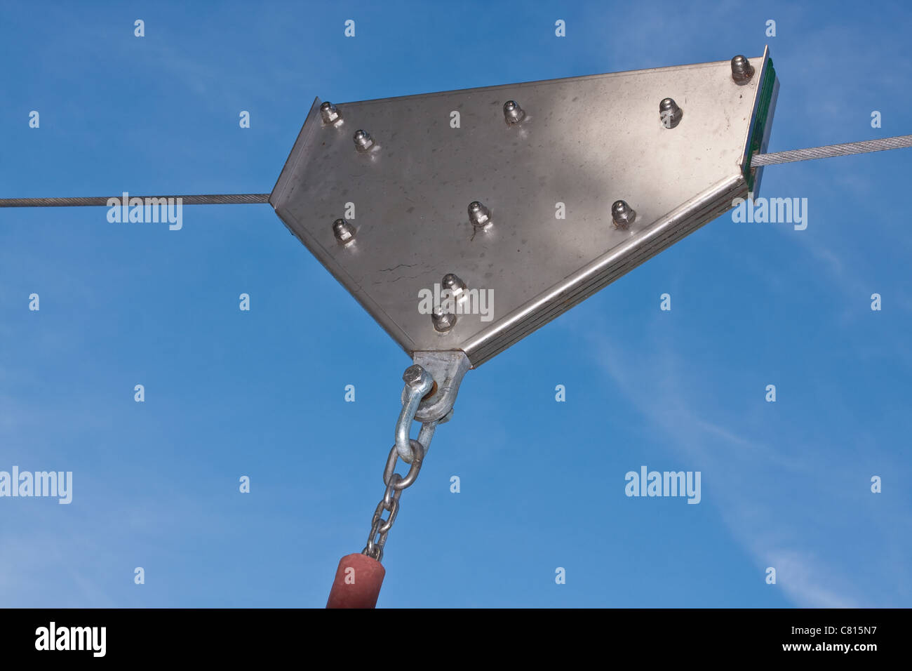 The pulley of a playground zip line against a bright blue sky Stock