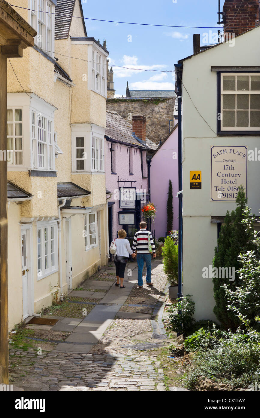 Couple walking past the Bath Place Hotel toward the entrance to the famous Turf Tavern pub, Bath Place, Oxford, Oxfordshire, UK Stock Photo