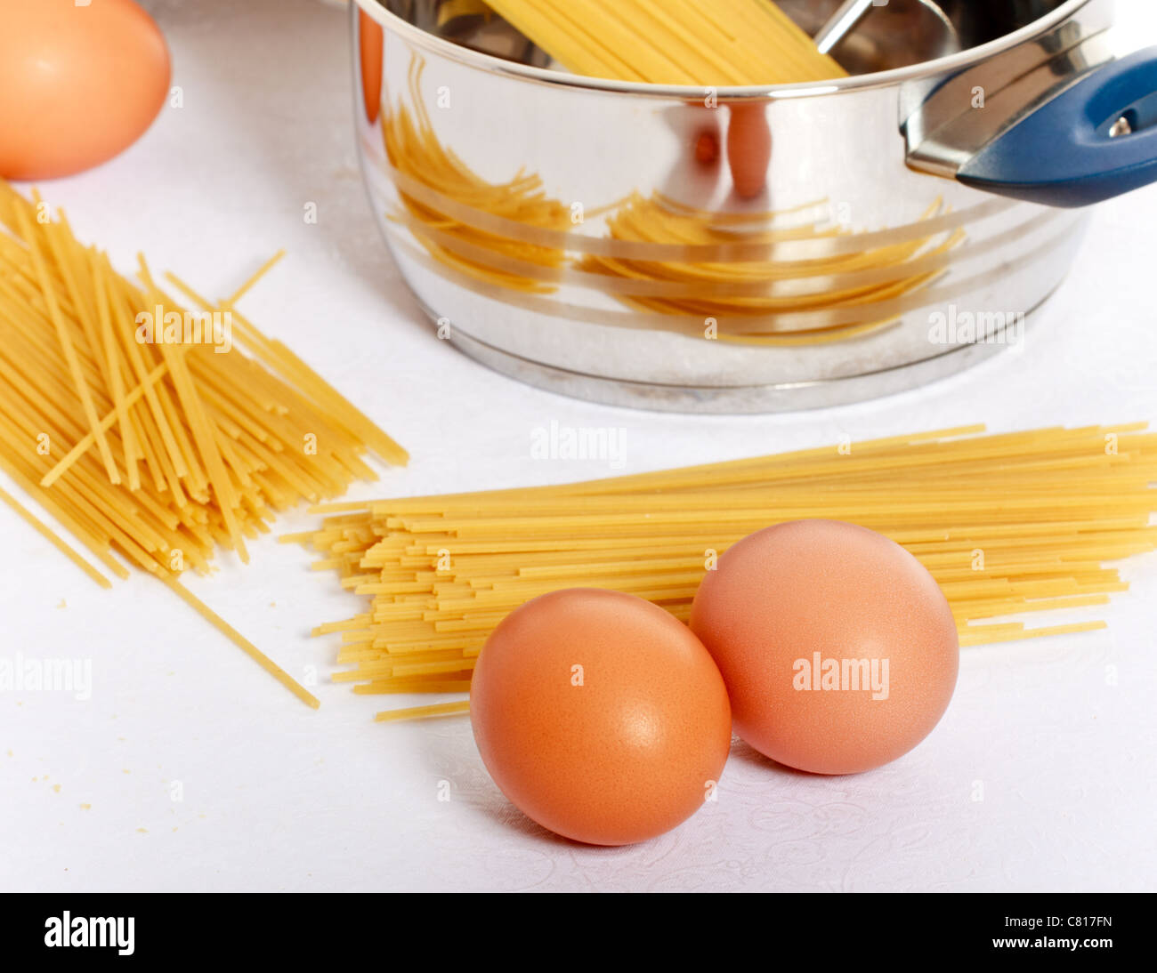 spaghetti, eggs and kitchen utensil on table Stock Photo