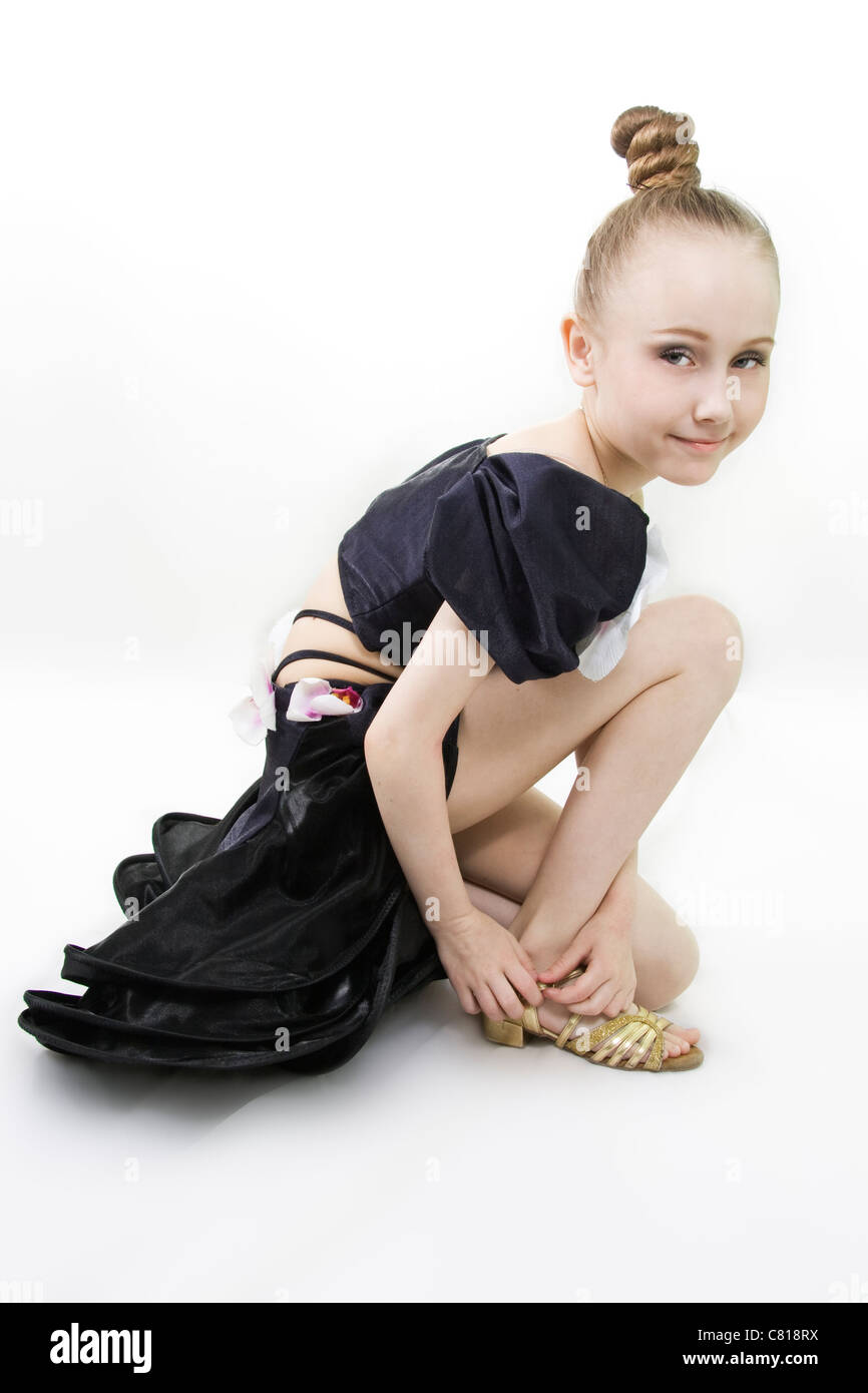 The dancing girl has sat down to clasp a shoe to a white background Stock Photo