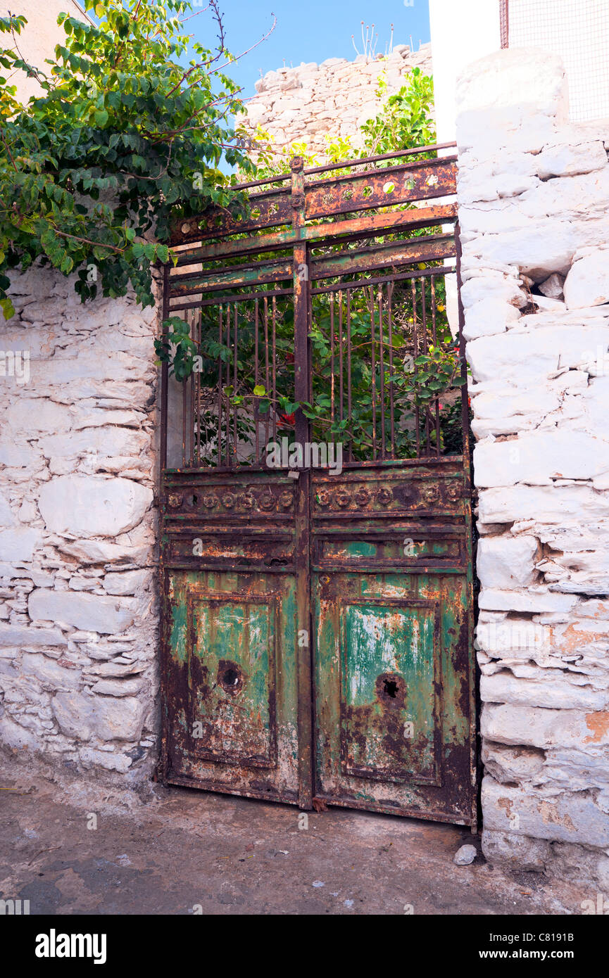 Old rusty door with peeling paint  leading to an abandoned courtyard on the Greek Cyclade island of Amorgos. Stock Photo