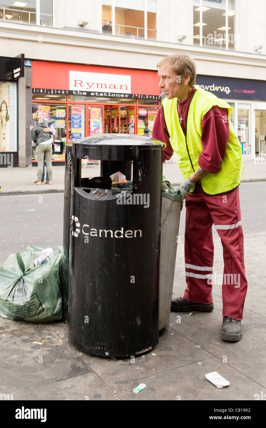 London Camden Town Lock Stables market Council worker in uniform hi vis jacket emptying street rubbish refuse garbage bin smoking Stock Photo