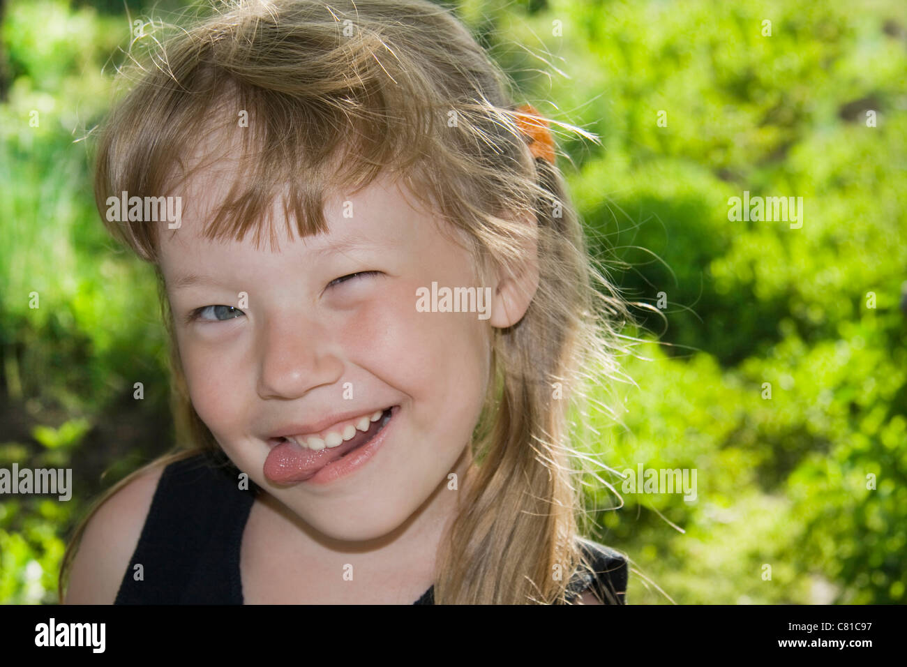 Little girl grimaces and sticking out tongue. Stock Photo