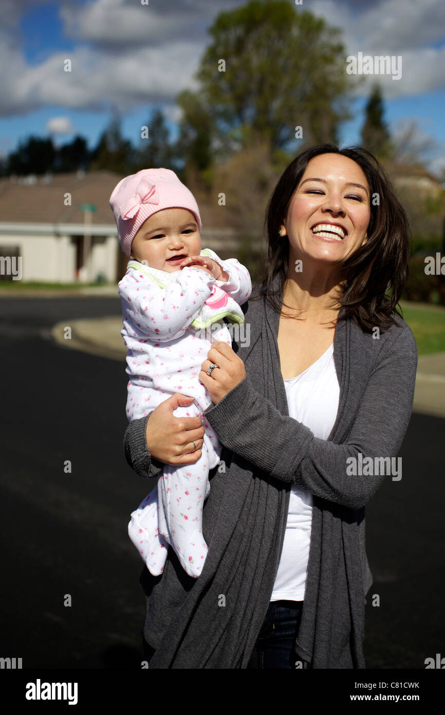 Mixed race mother holding baby girl outdoors Stock Photo