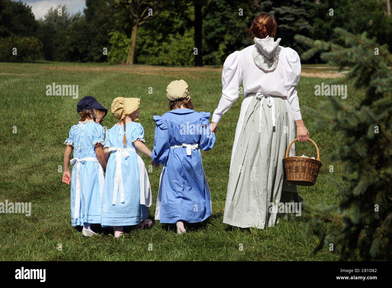 A woman holding hands with three girls Stock Photo - Alamy